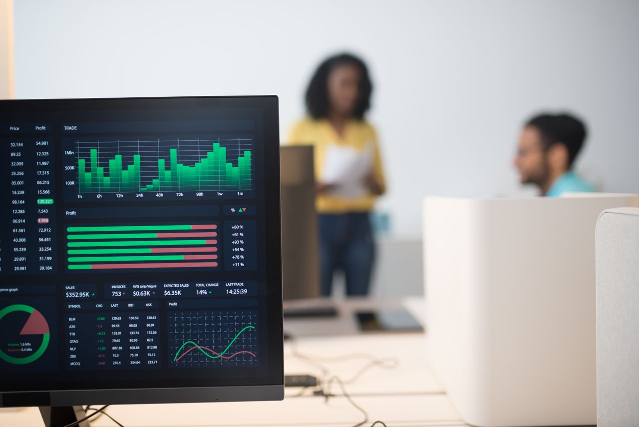 creative Modern office with financial trading screens and a diverse team discussing strategies.