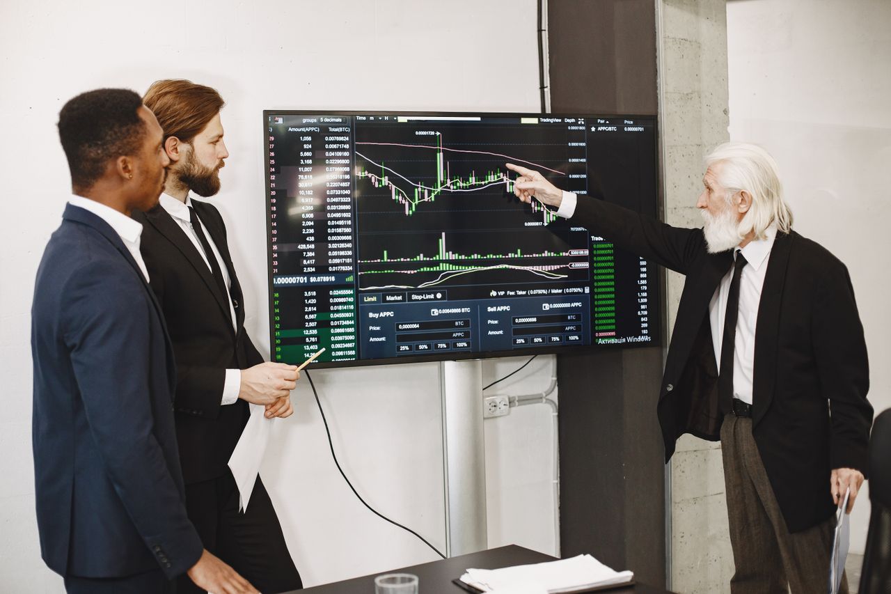 digital A diverse business team in a meeting analyzing stock market data on a screen.
