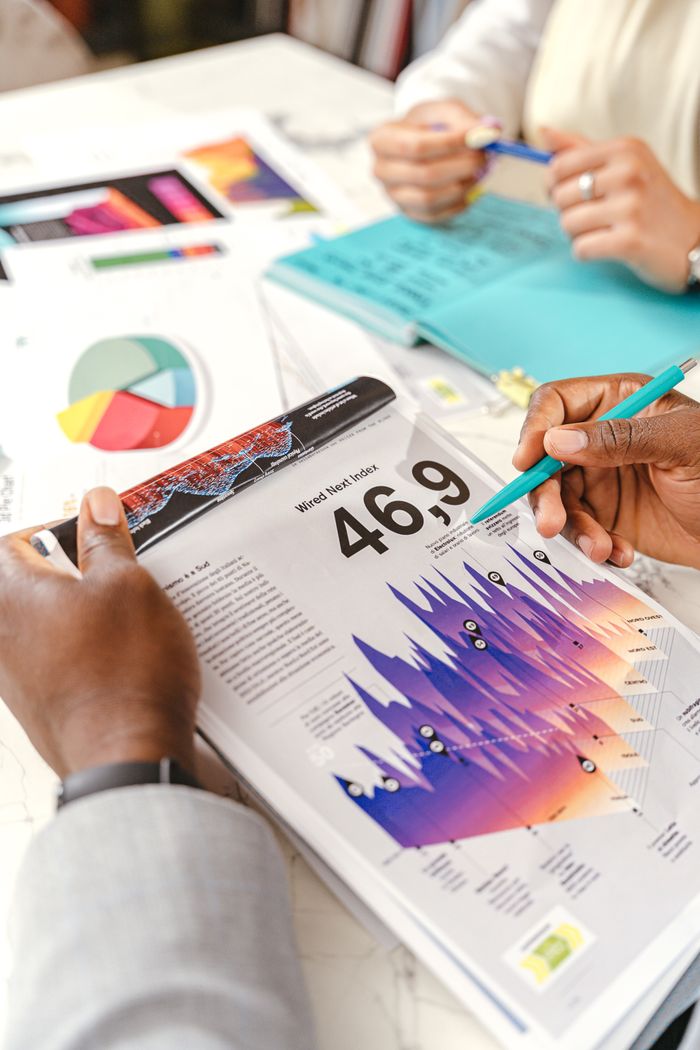 why-choose-us Hands discussing vibrant data charts during a business meeting, with papers and diagrams.